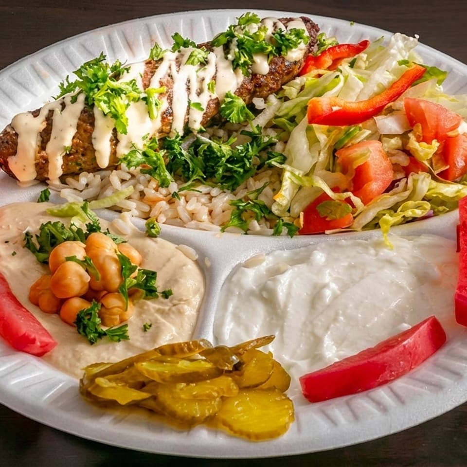 Kebab plate with rice, salad, hummus, yogurt, pickles, and pickled turnips on a white plate.
